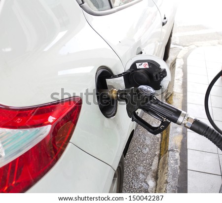 Pumping gas at gas pump. Closeup pumping gasoline fuel in car at gas station.