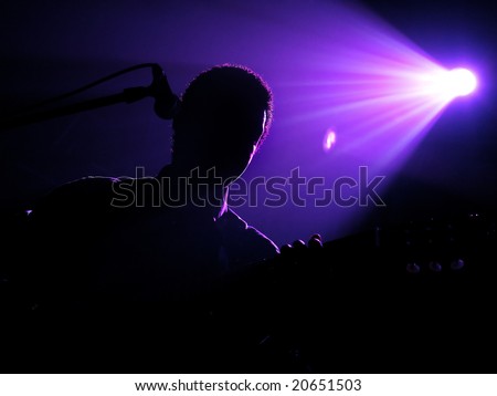 Silhouette of the playing guitarist under beams of violet light