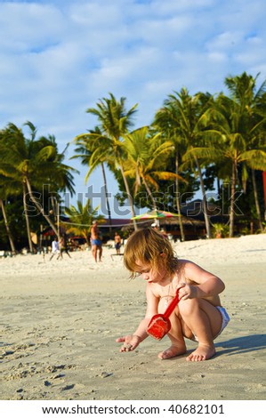 Girl plays on the sand with the toys