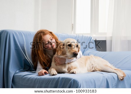 Little girl and dog on a sofa near the window