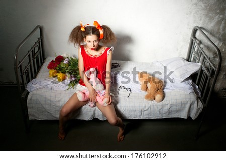 Girl with a toy in the hands sitting on the bed