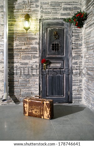 Old suitcase at the door and flower in the handle of door