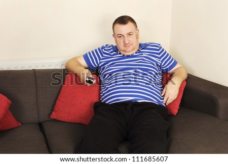 bored man on sofa holding a TV remote control
