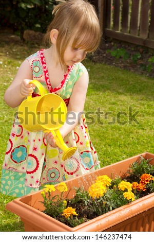 Pre-school child watering flowers in a garden with a watering can