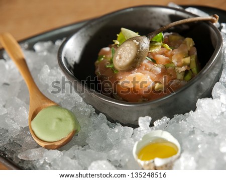 Salmon tartar on ice bed with egg and sauce. high cuisine