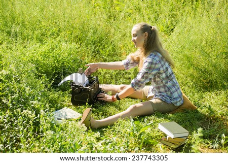 beautiful young blonde woman typing on a typewriter at outdoor