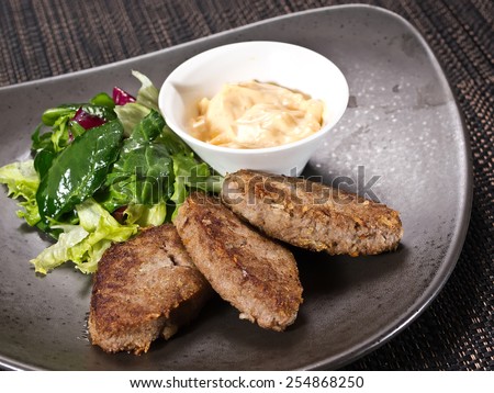 three beef Patties with Yogurt, Sour Cream and salad on black background