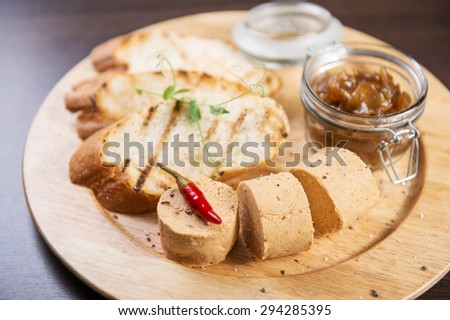 Chicken liver pate on wooden board decorated with pepper chilly