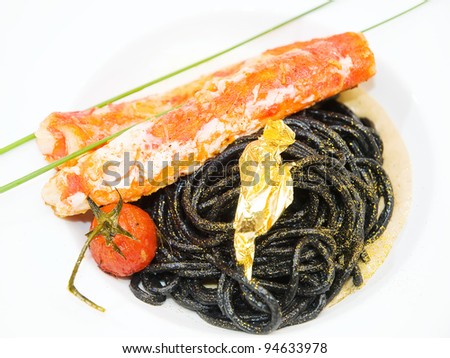 black pasta with tomato and crab fillet decorated with gold
