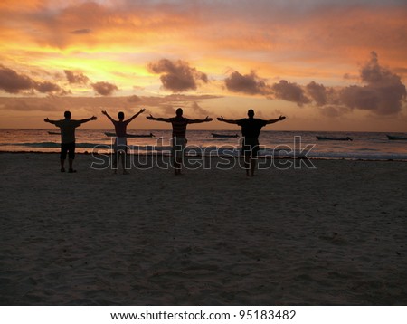 Four people on the beach at sunrise all in silhouette