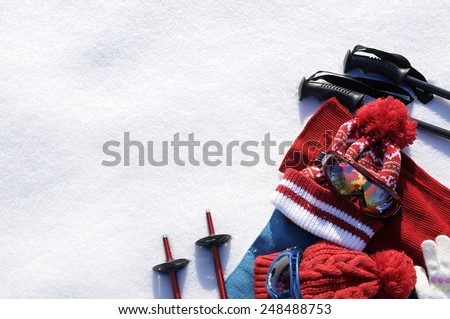 Winter snow sports skiing background with ski poles, goggles, bobble hats and gloves.  Space for copy.