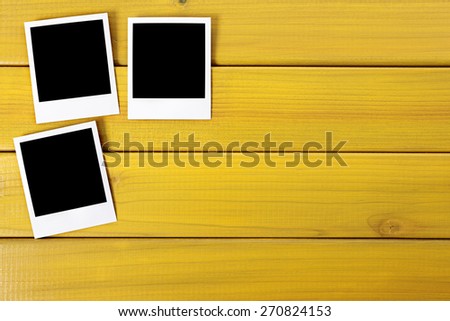 Three blank polaroid photo prints, wood background, copy space