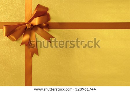 Christmas or birthday gift background gold shiny metallic foil with deep honey gold ribbon and bow