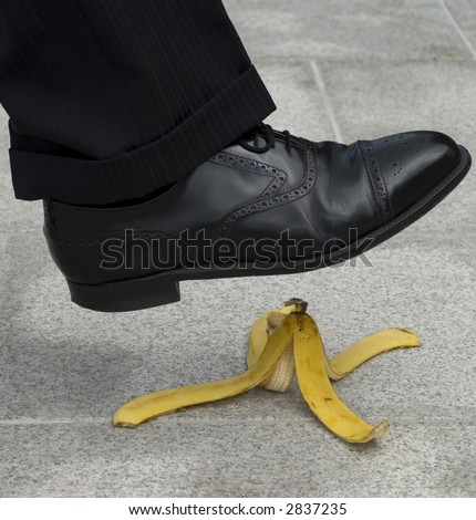 A businessman about to have an accident by stepping on a banana skin or peel.