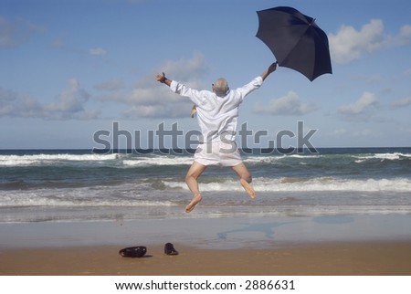 Senior business man undressed and jumping with happiness and freedom on a beautiful beach. Retirement, vacation or stress free concept.  Copy space.