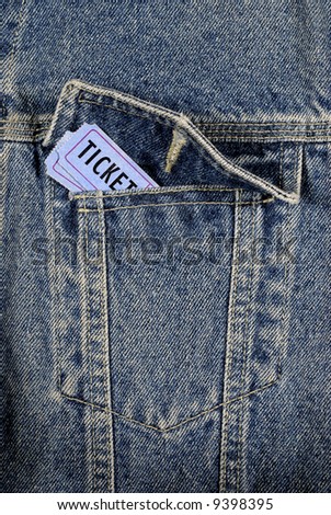 Two blue movie or concert tickets tucked inside the front pocket of a denim jeans jacket.