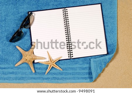 Beach scene with starfish, towel, sunglasses and blank writing book
