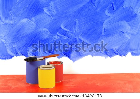 Partly painted blue wall with red floor, paint and paintbrushes