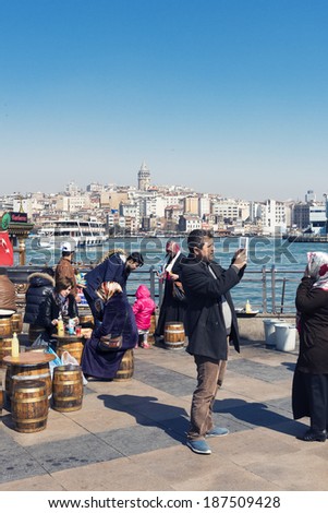 ISTANBUL, TURKEY - APRIL 06, 2014:crowd in Eminou District. Eminonu Square, people eating fish. Eminonu Square is so crowded on day.People watching golden horn.