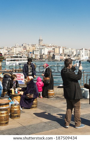 ISTANBUL, TURKEY - APRIL 06, 2014:Walking of crowd in Eminou District. Eminonu Square, people eating fish. Eminonu Square is so crowded on day.People watching golden horn.