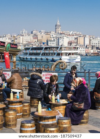 ISTANBUL, TURKEY - APRIL 06, 2014:crowd in Eminou District. Eminonu Square, people eating fish. Eminonu Square is so crowded on day.People watching golden horn.