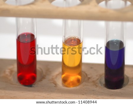 A wooden test tube rack with 3 test tubes containing colourful liquids