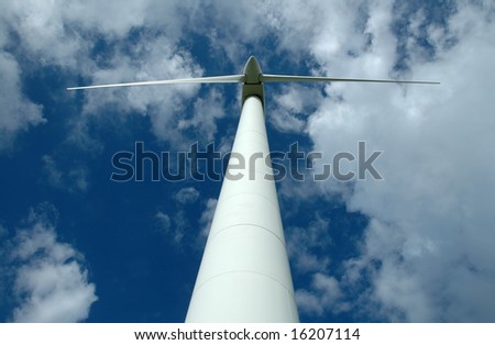 A view of a white wind generator from the ground