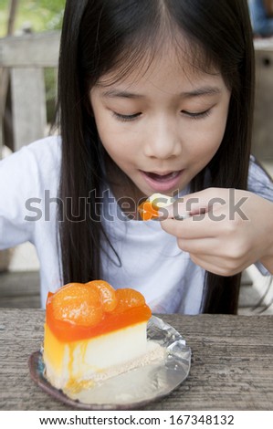 Beautiful Asian girl enjoy dessert orange cheese pie cake.