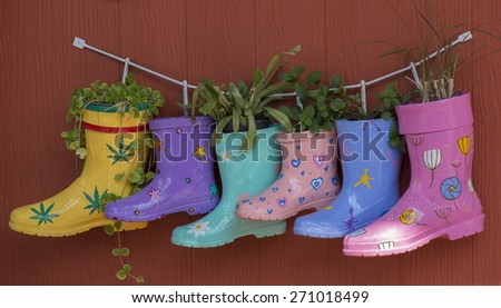 Colorful rubber boot decoration on wooden wall as plant jardiniere.