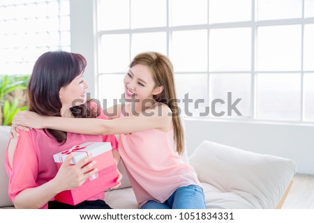 daughter give her mother gift and smile happily at home