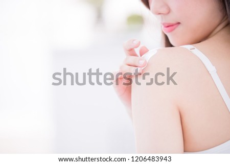 Young skin care woman applying body lotion on arm and shoulder at home