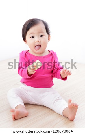Little Baby Girl eat cookies and sticking her tongue out on living room at home, asian child