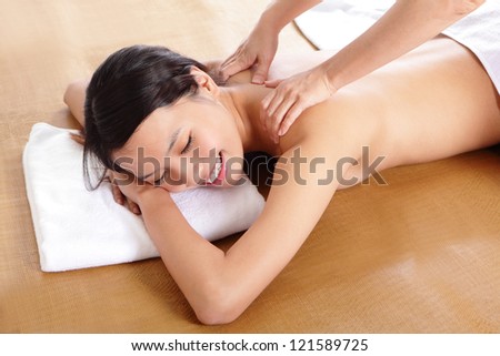 Woman in beauty salon having massage of shoulder, asian woman model