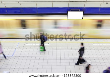 people walking on platform at a metro railway station with motion blur speed train and blank tv billboard, shot in Taipei, Taiwan, asia