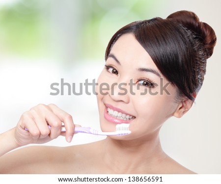 Young smiling woman cleaning teeth with toothbrush with nature green background, asian beauty model