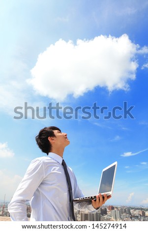 Young business man using laptop and look to blue sky and cloud with cityscape in the background, business and cloud computing concept