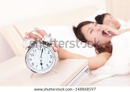 Wake up - Tired couple touch the alarm clock while they are sleeping in bed, asian family
