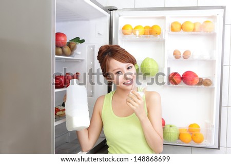 Healthy Eating Concept .Diet. Beautiful Young Woman drink milk near the Refrigerator. Fruits and Vegetables, asian model