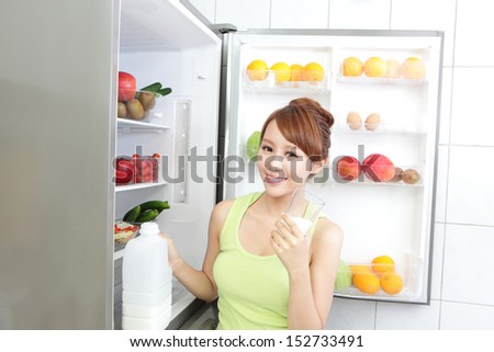 Healthy Eating Concept .Diet. Beautiful Young Woman drink milk near the Refrigerator. Fruits and Vegetables, asian model