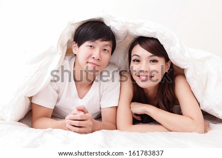 young lovely couple lying in a bed, happy smile looking to camera, asian people