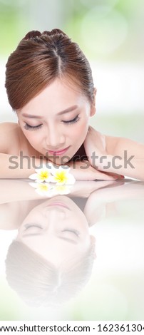 Beautiful face beauty woman lying down with flower and mirror reflection. SPA concept, asian beauty