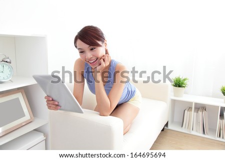 happy woman using tablet pc on sofa in the living room at home, asian beauty