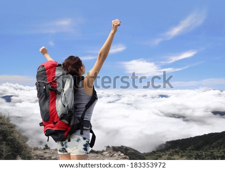happy woman with backpack raised arm hands and looking to sky on the top of mountains. asian