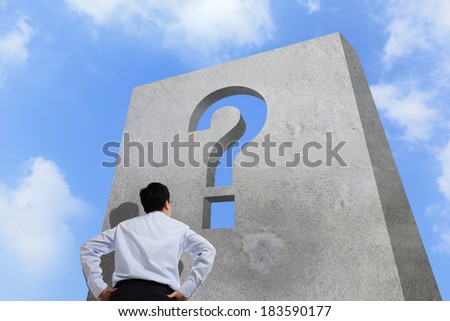 Business man watching question mark wall