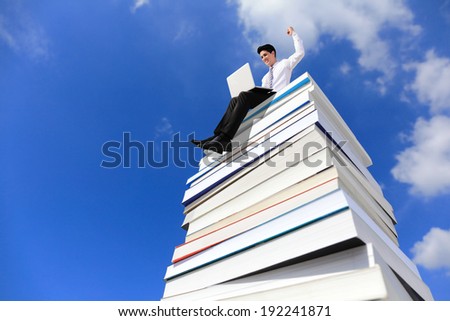 Knowledge is power - Happy business man using pc computer and sitting on a stack Of Books