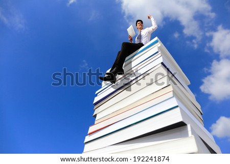 Knowledge is power - Happy business man using tablet pc computer and sitting on a stack Of Books