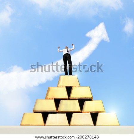 Successful business man standing on gold bullion with sky and growth arrow cloud
