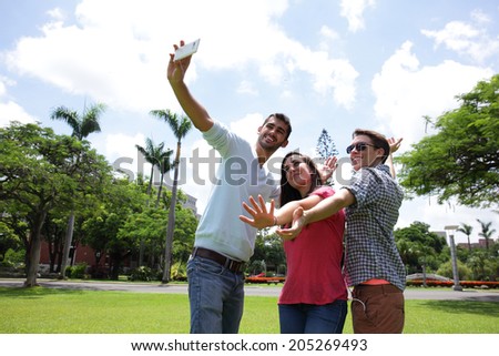 Group of happy friends taking a selfie on a blue sky in campus lawn, caucasian