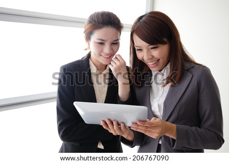 Business women look and smile conversation with Digital Tablet in Office, asian