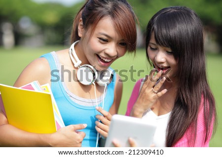 Happy girl College students smile look digital tablet pc on campus lawn, asian